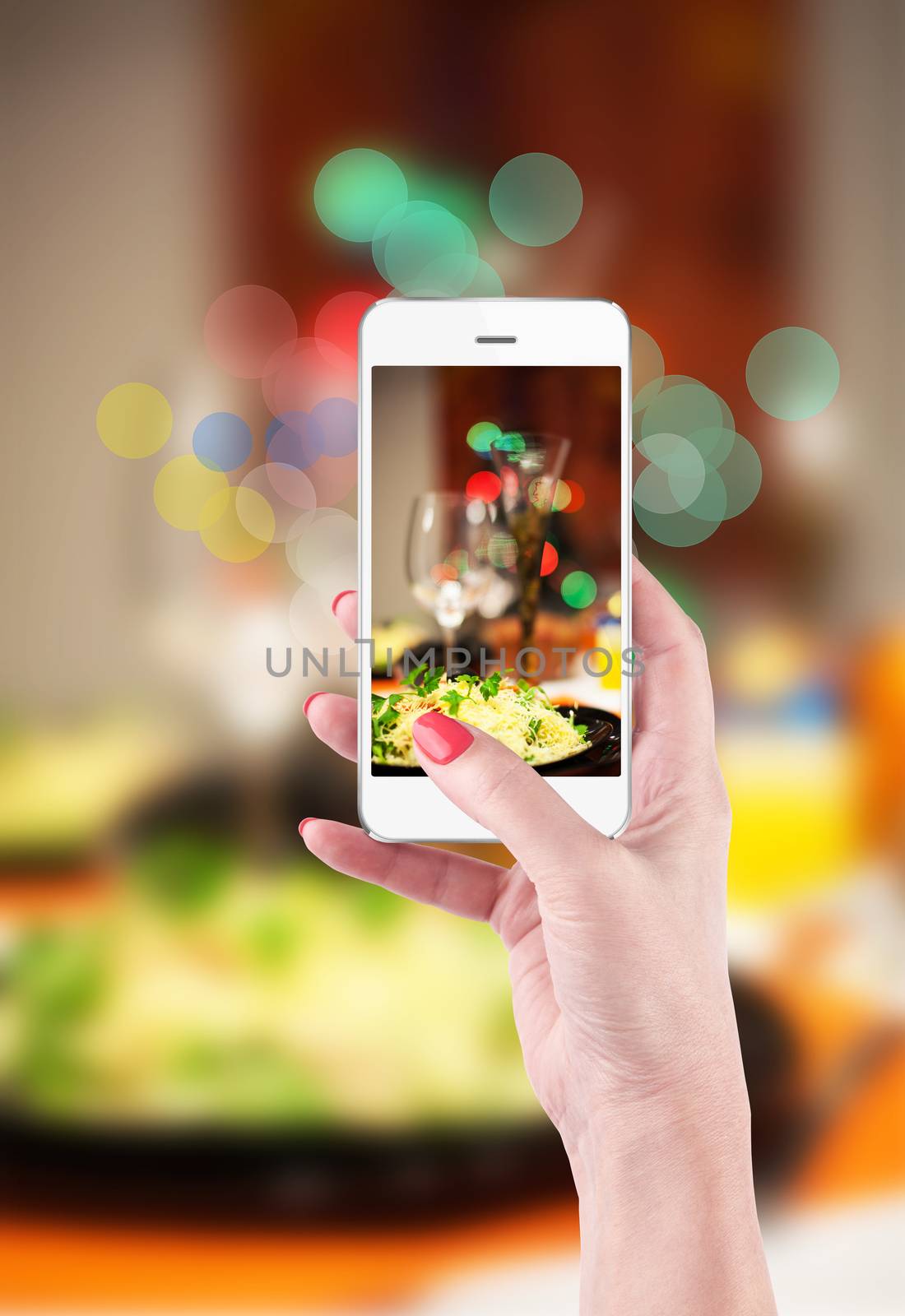 Female hand holding smartphone to take pictures of food and table setting