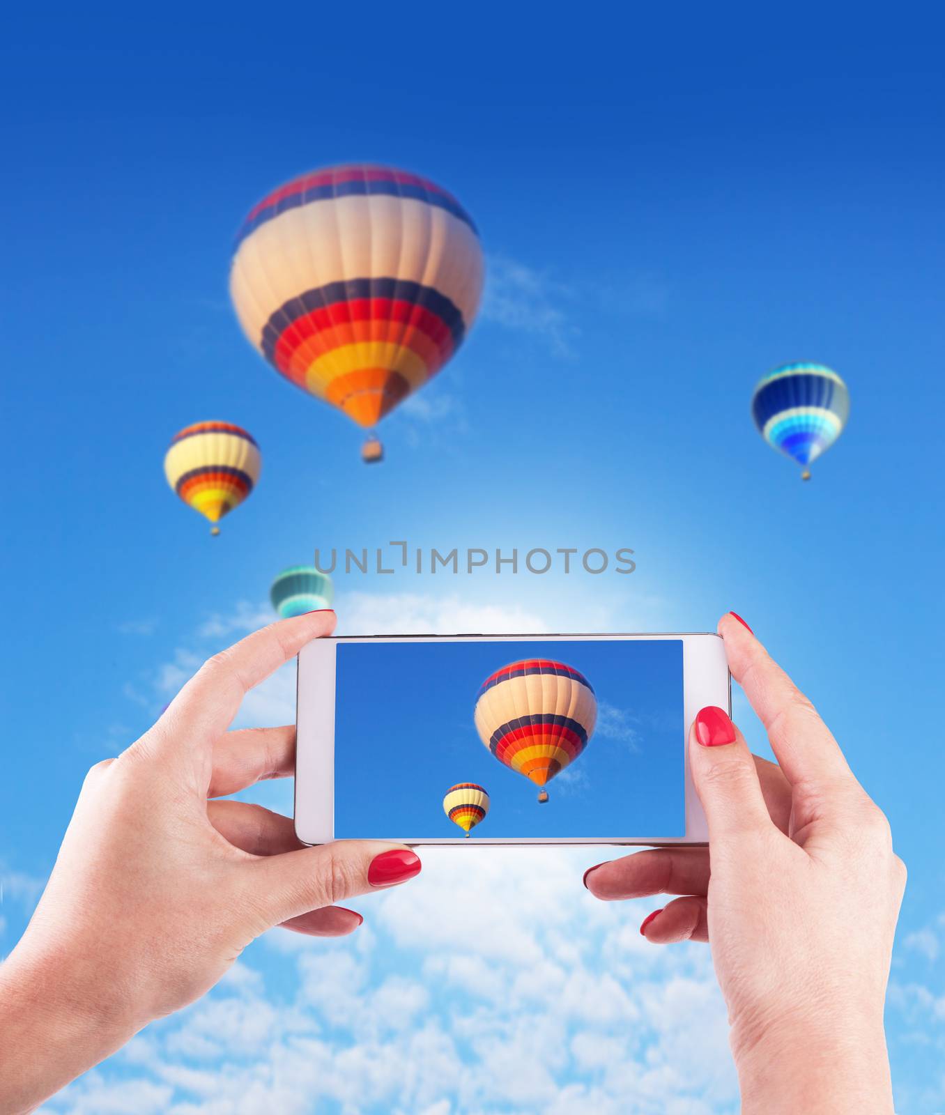 Female Hands Holding Smart Phone Photo of Blue Sky with Hot Air  by SlayCer