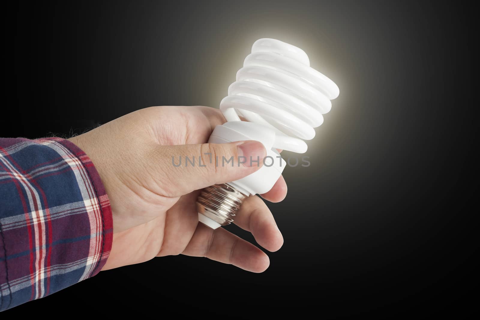 Energy saving lamp in the man's hand on black background closeup.  With clipping path