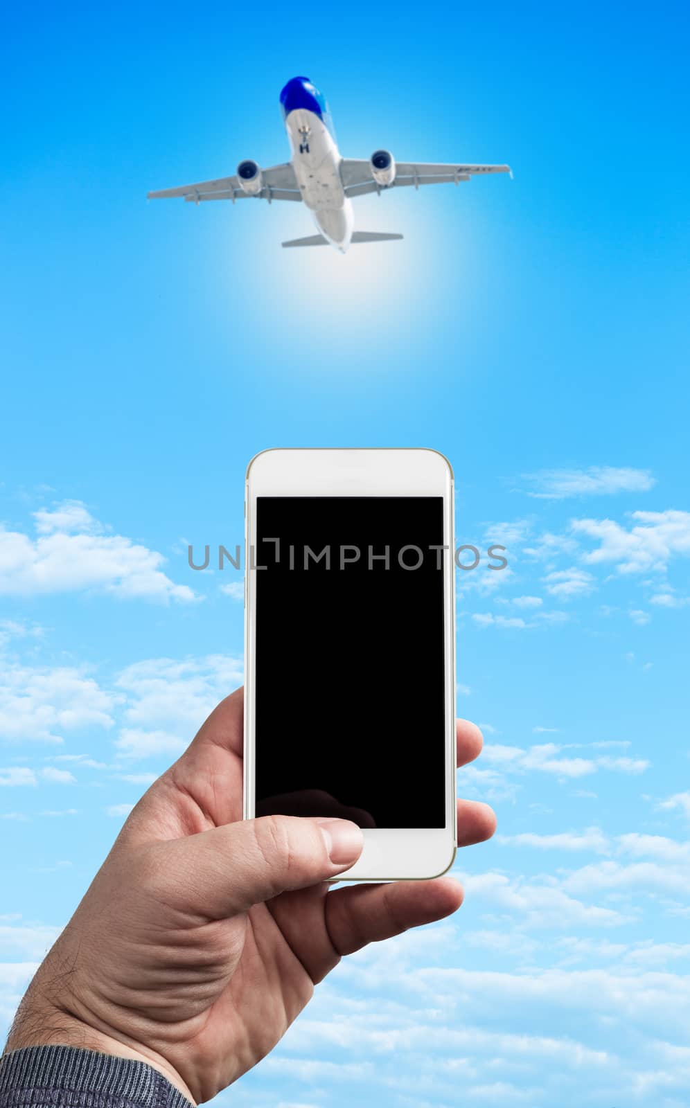 Man Hand holding using mobile phone and airplane on a blue background