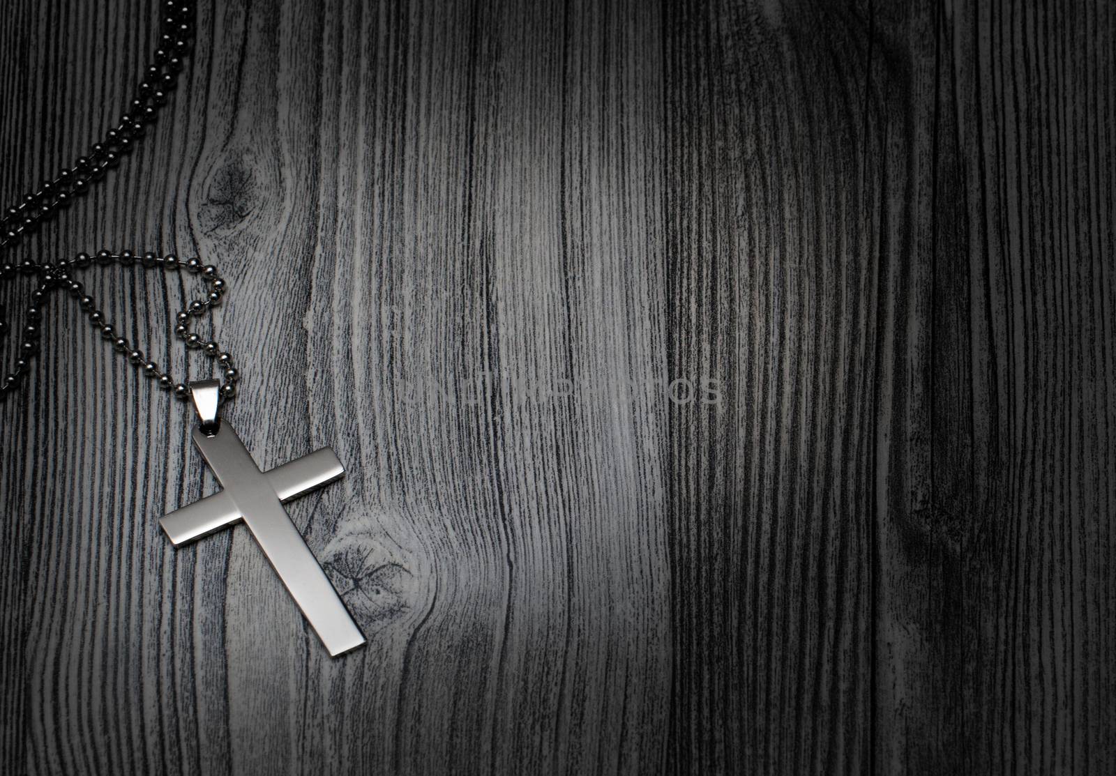 Metal cross on a wooden background
