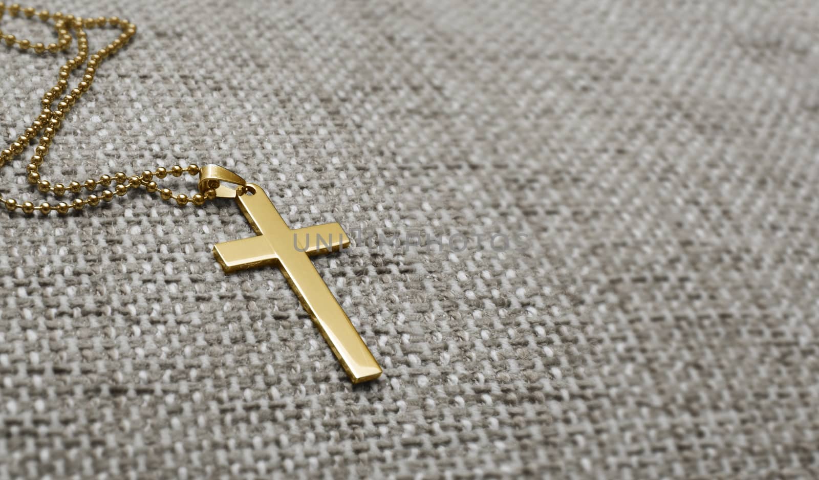 Gold metal cross on a background of rough cloth