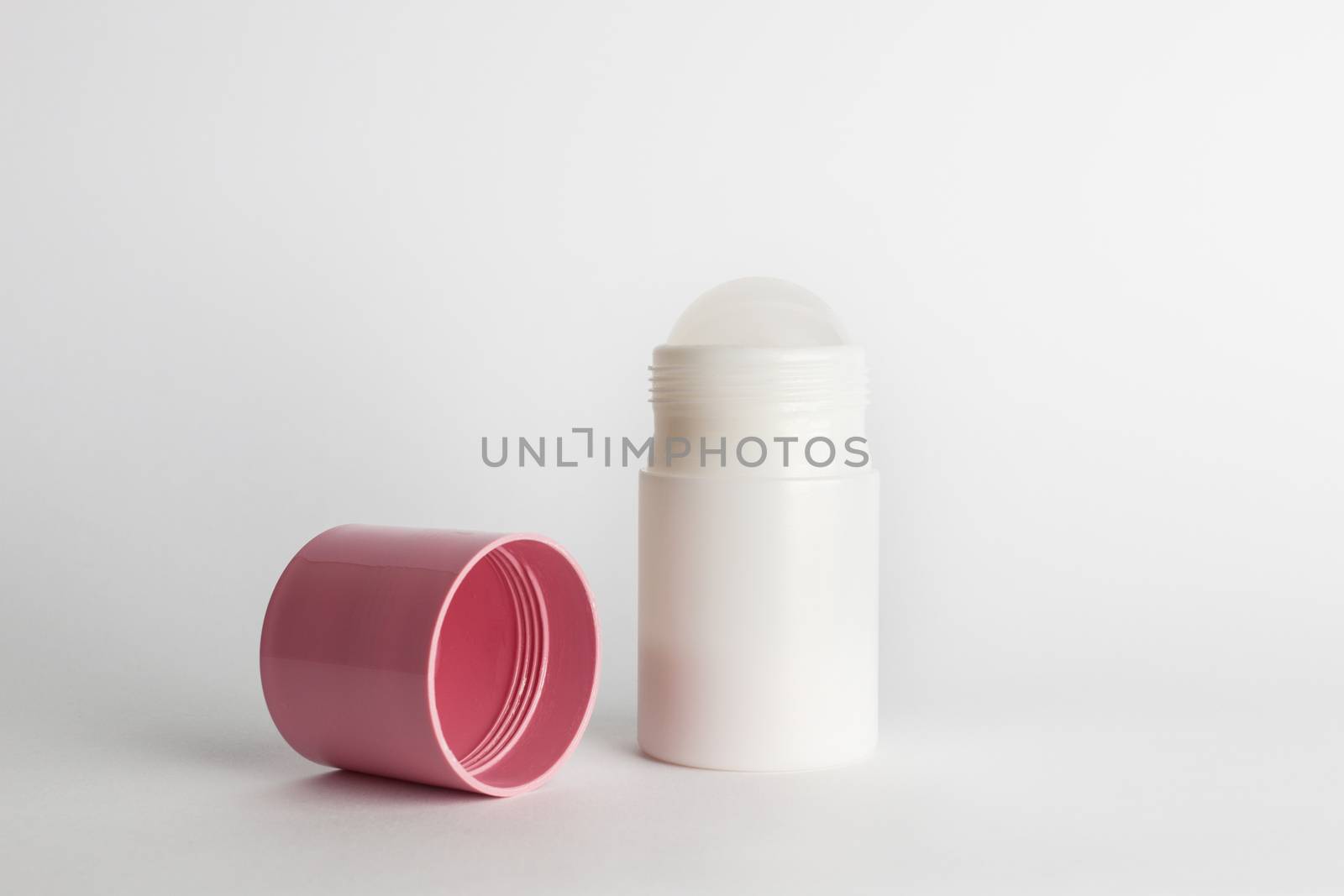 Roll-on antiperspirant cosmetic and pink cover isolated on white background
