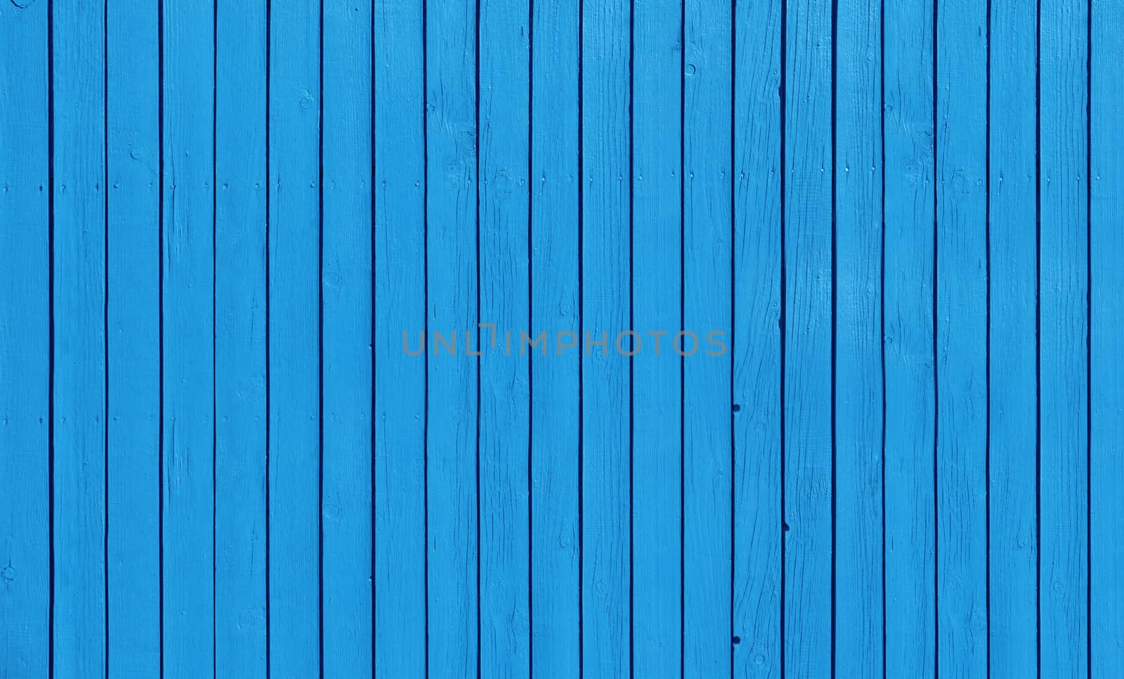 Wooden slat fence with parallel planks with blue paint.
