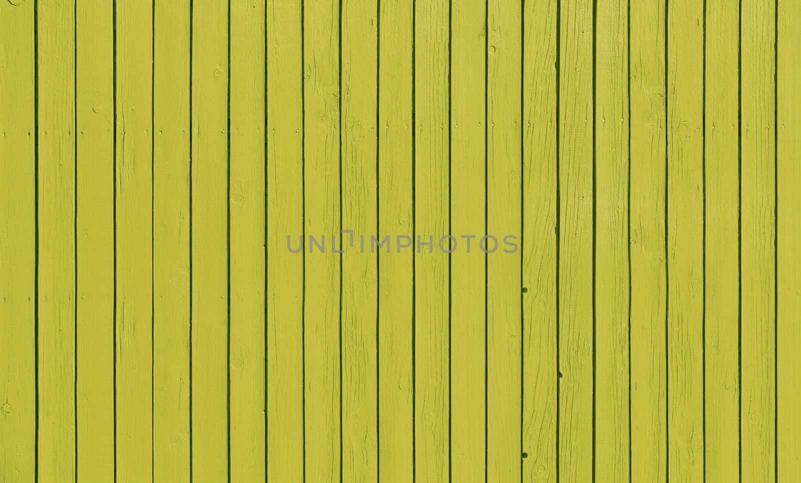 Wooden slat fence with parallel planks with yellow paint.