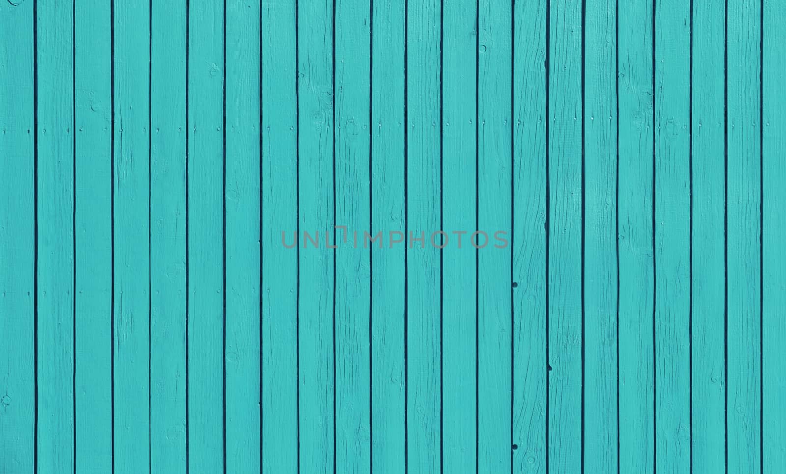 Wooden slat fence with parallel planks with blue paint.
