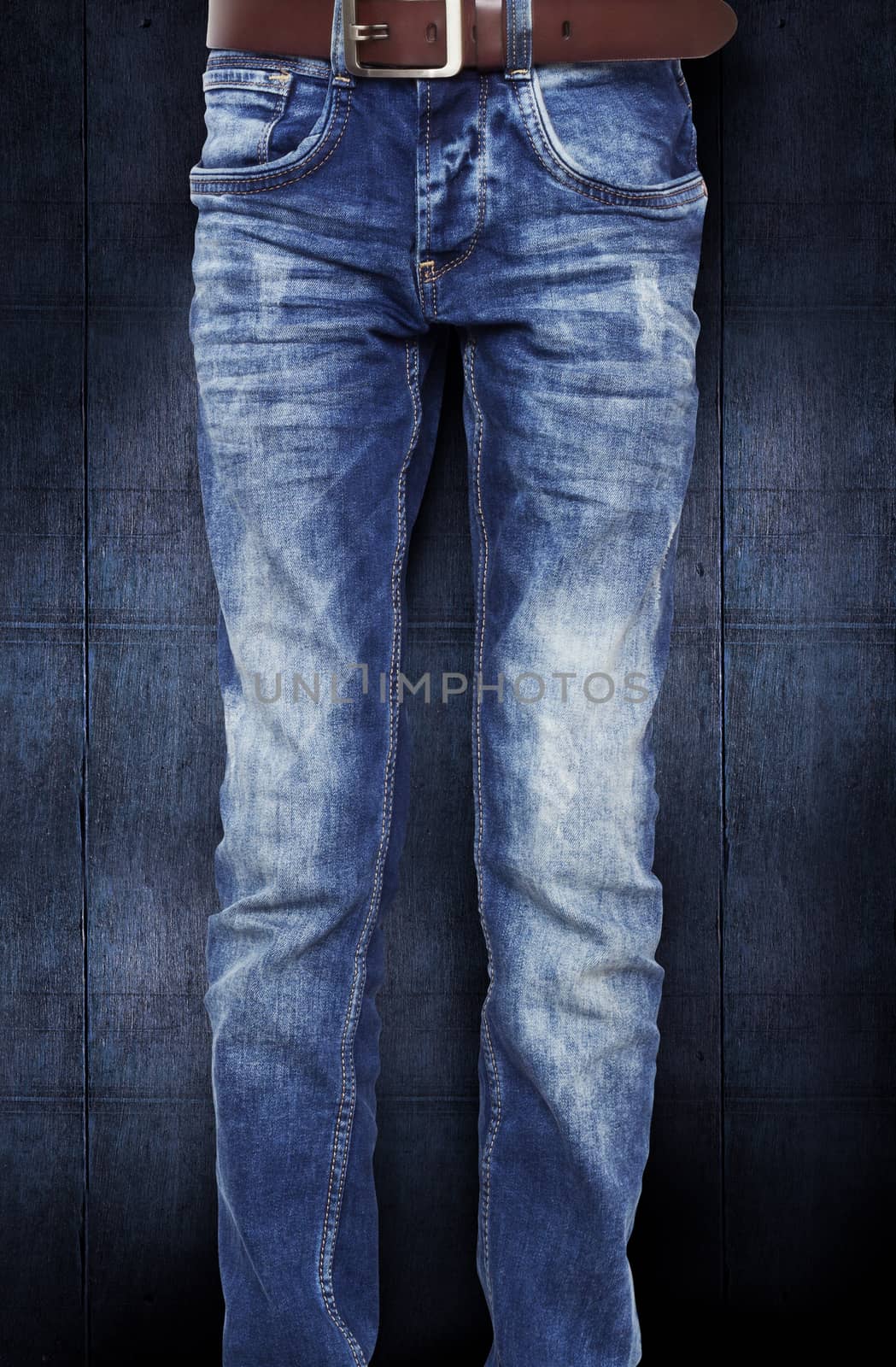 Blue jeans for the teenager with a belt. On a dark blue background wood texture. With clipping path