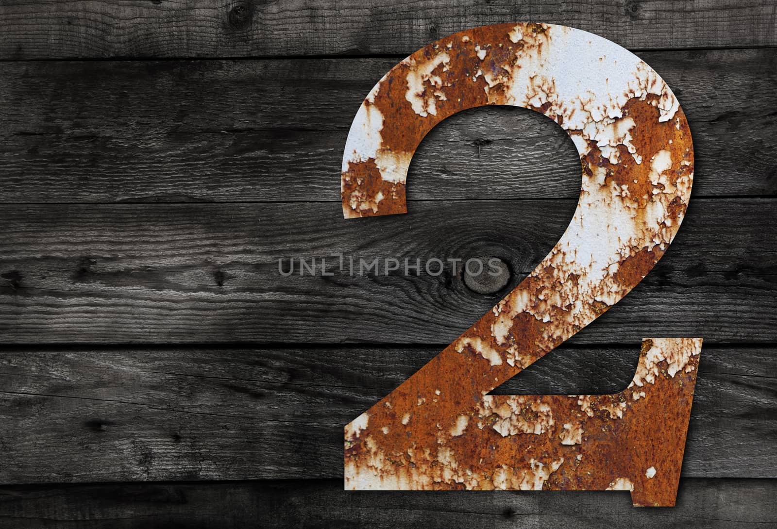 Old rusty metal alphabet, text 2 on Wooden Background nails.