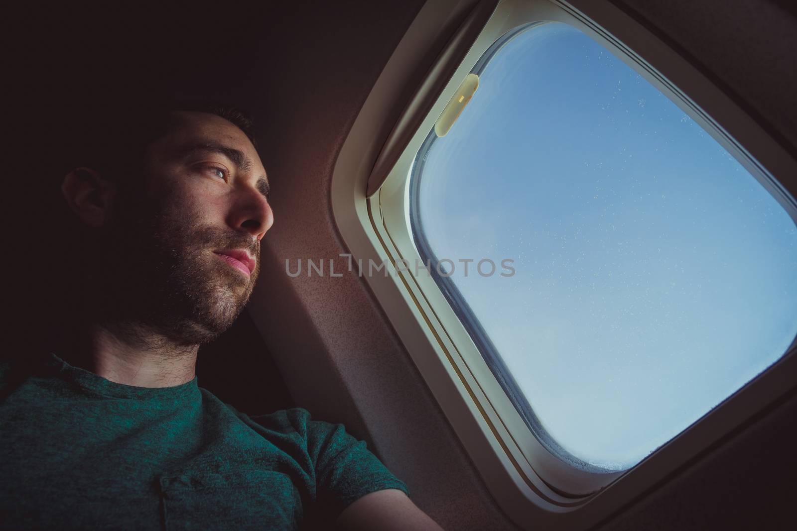 Pensive man looking outside through the window of an airplane.