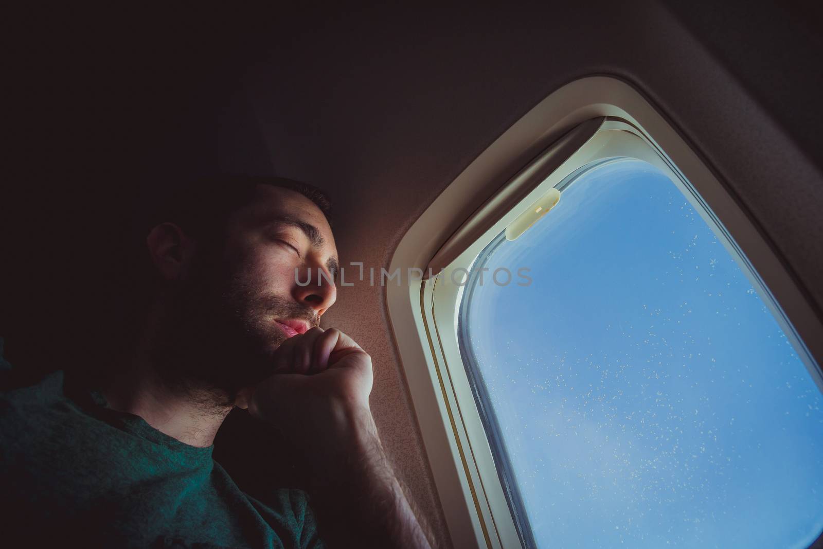 Young man resting and sleeping on an airplane.