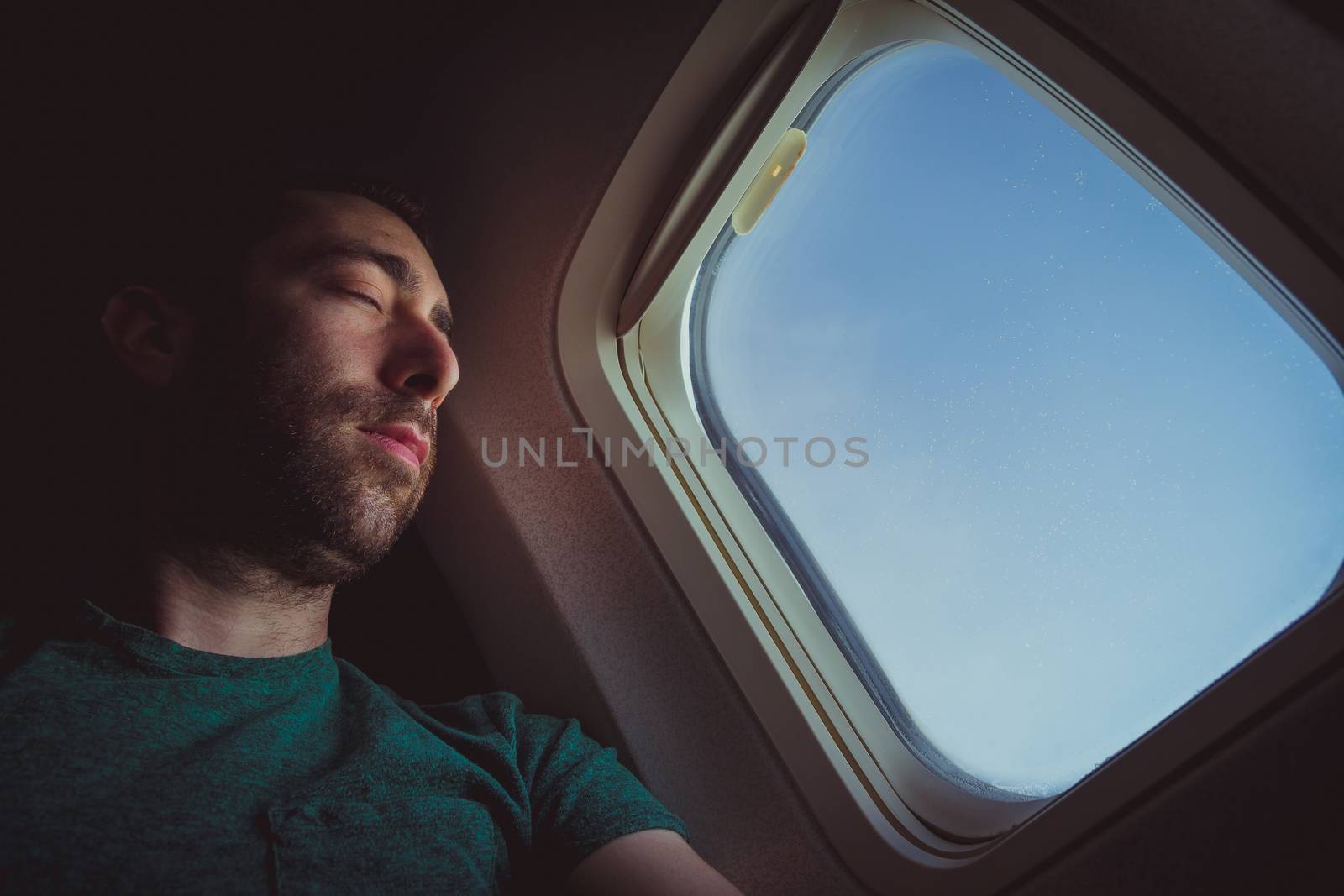 Young man resting and sleeping on an airplane.