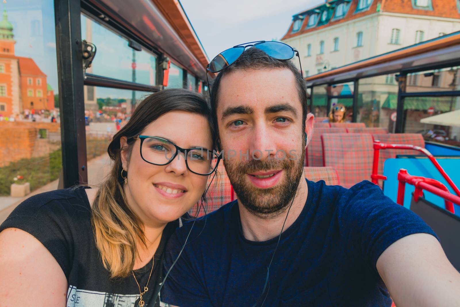 Happy couple taking a selfie with smartphone or camera inside a city tour bus.