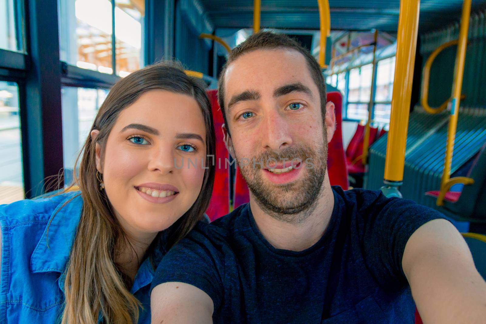 Happy couple taking a selfie with smartphone or camera inside a city bus.