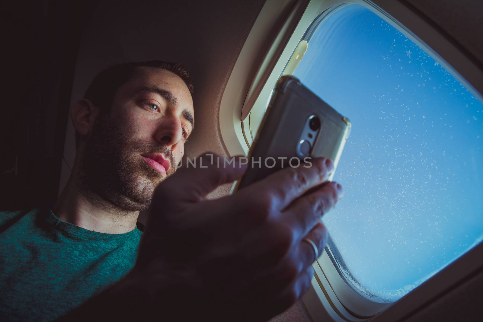 Young man looking at his smartphone and using it while seating b by wavemovies