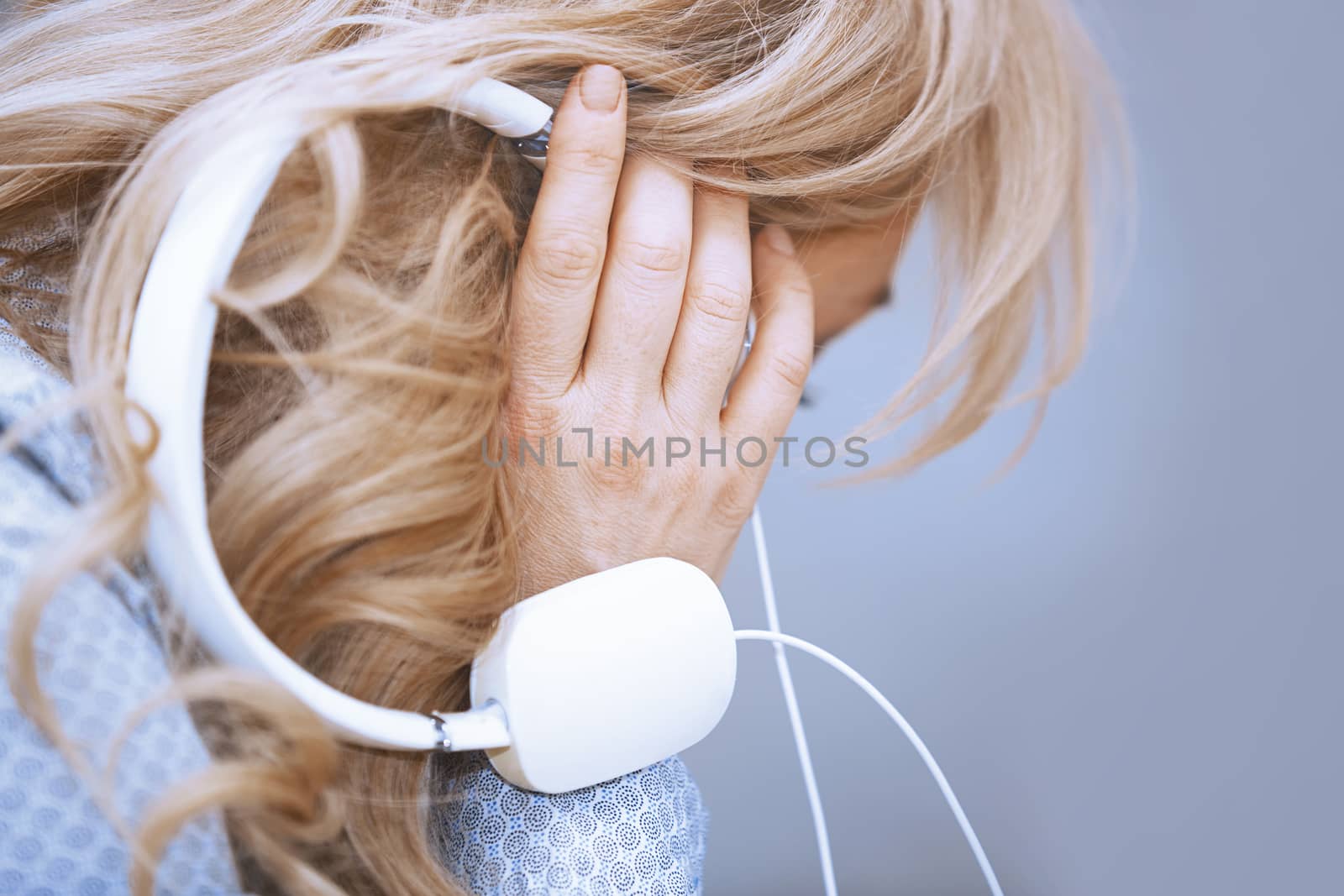 Blond woman listening music via headphones by Novic