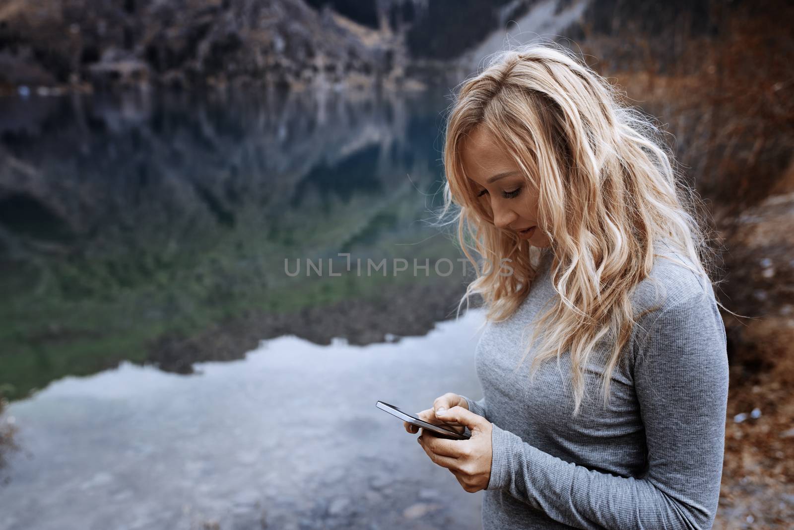 Woman using smartphone at the mountain lake