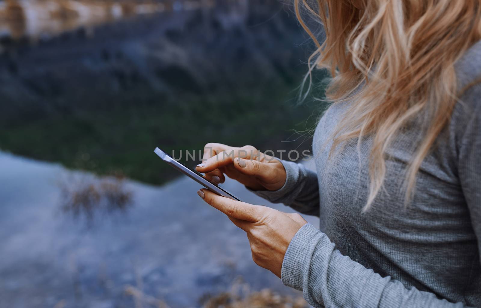 Woman using smartphone at the lake by Novic