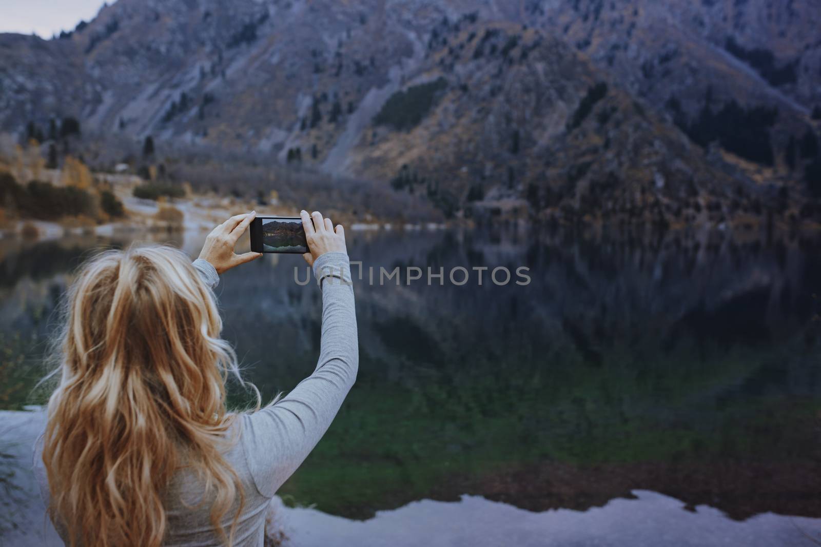Woman making mobile photo at the mountain lake by Novic