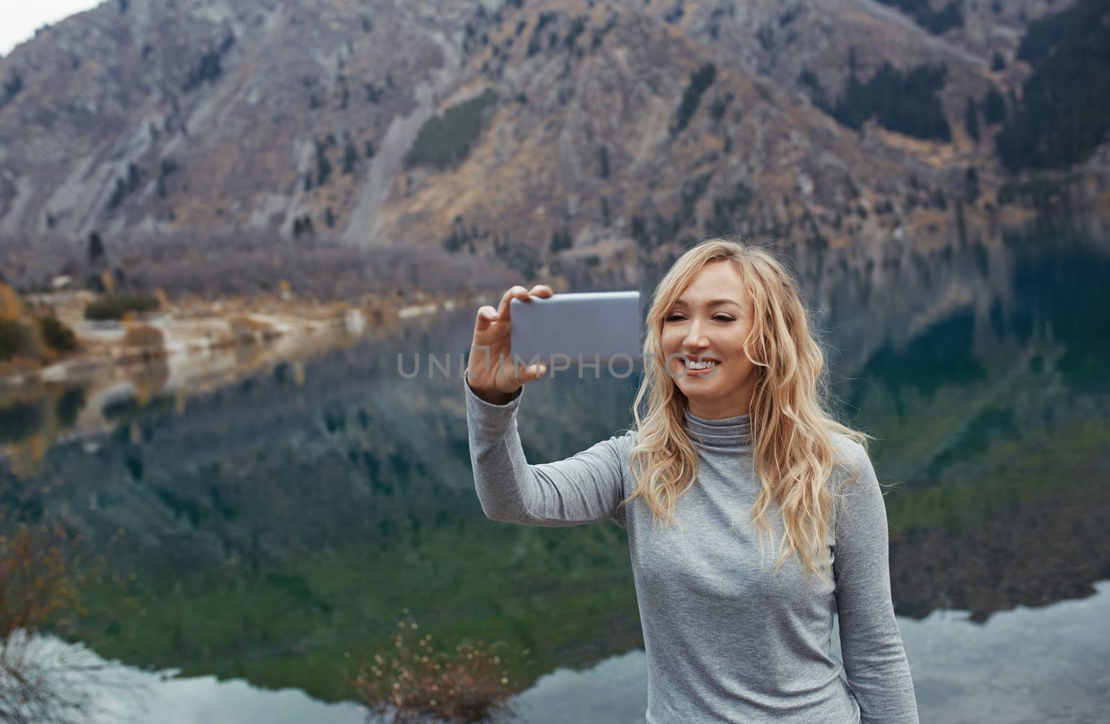 Smiling woman makes selfie at the mountain lake by Novic