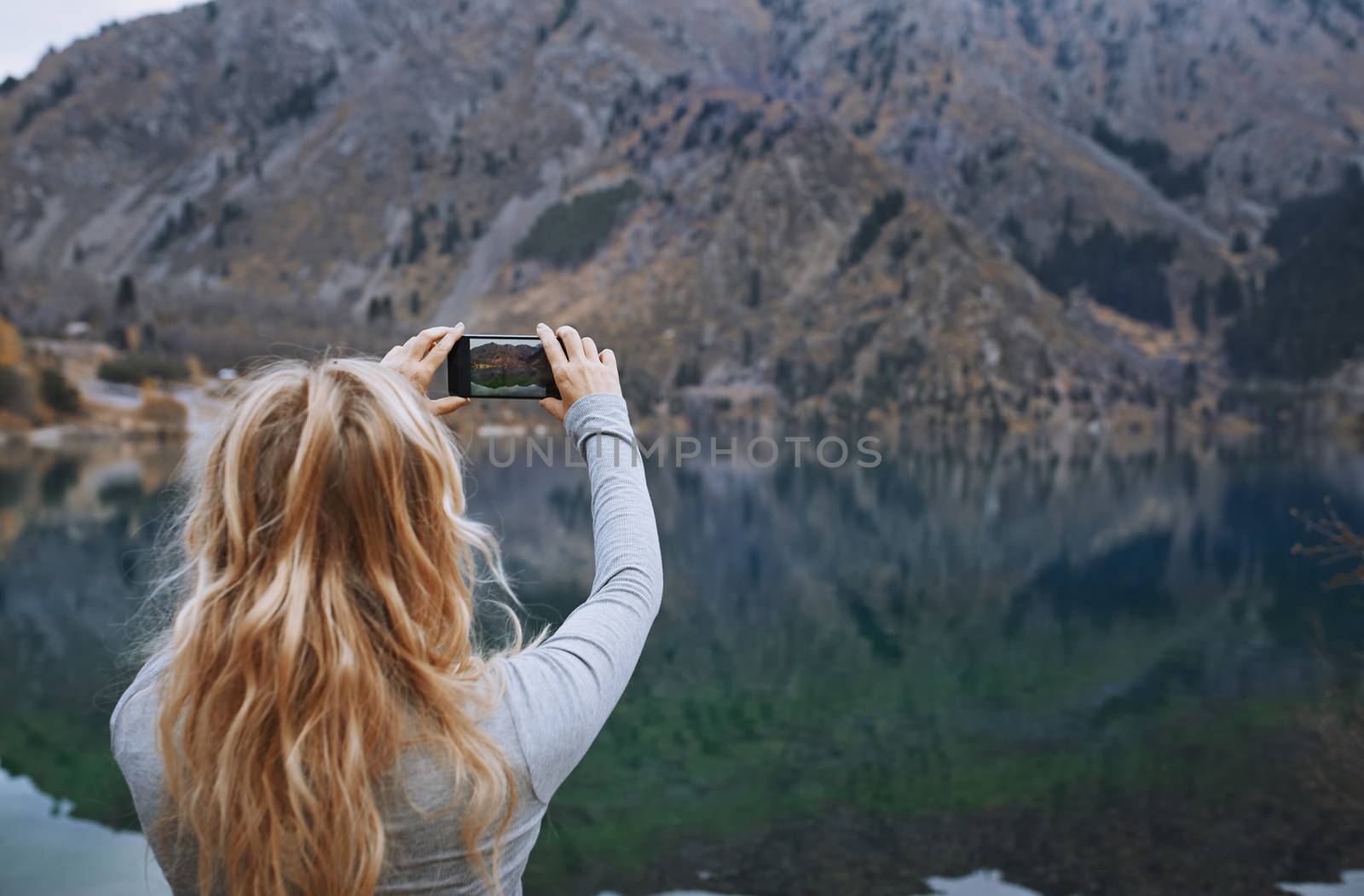 Woman making mobile photo at the mountain lake by Novic