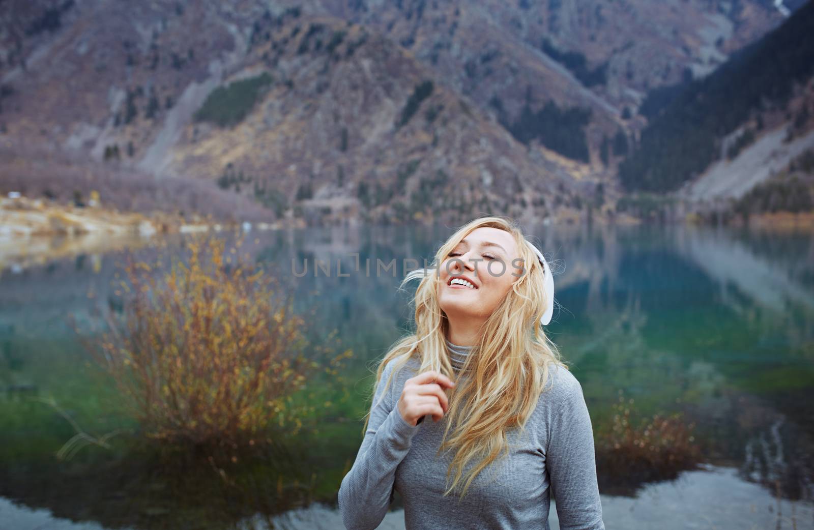 Woman wearing wireless headphones at the lake by Novic