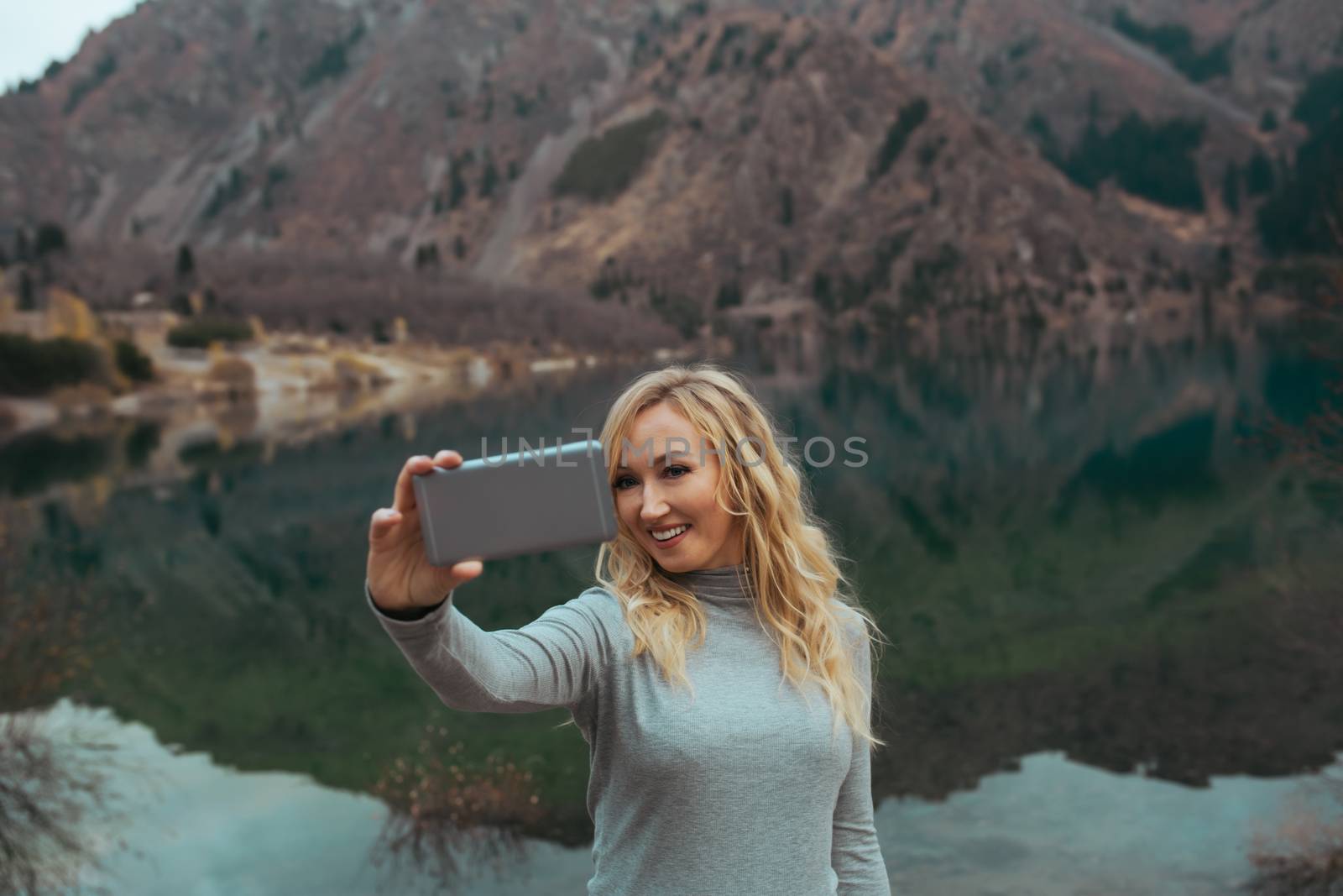 Smiling woman makes selfie at the mountain lake by Novic