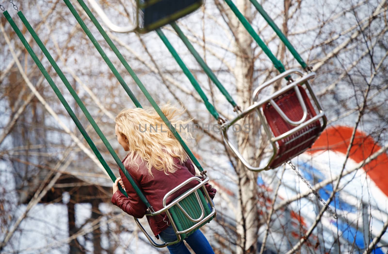 Blond woman riding on a chain swing by Novic