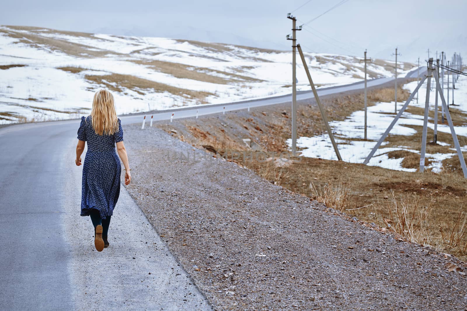 Woman walking along the rural highway by Novic