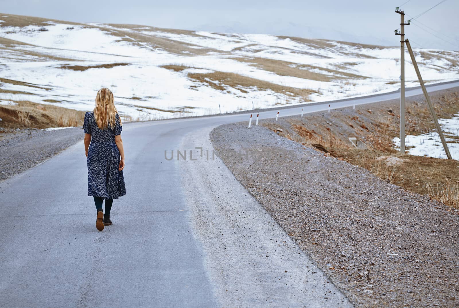 Woman walking along the rural highway by Novic