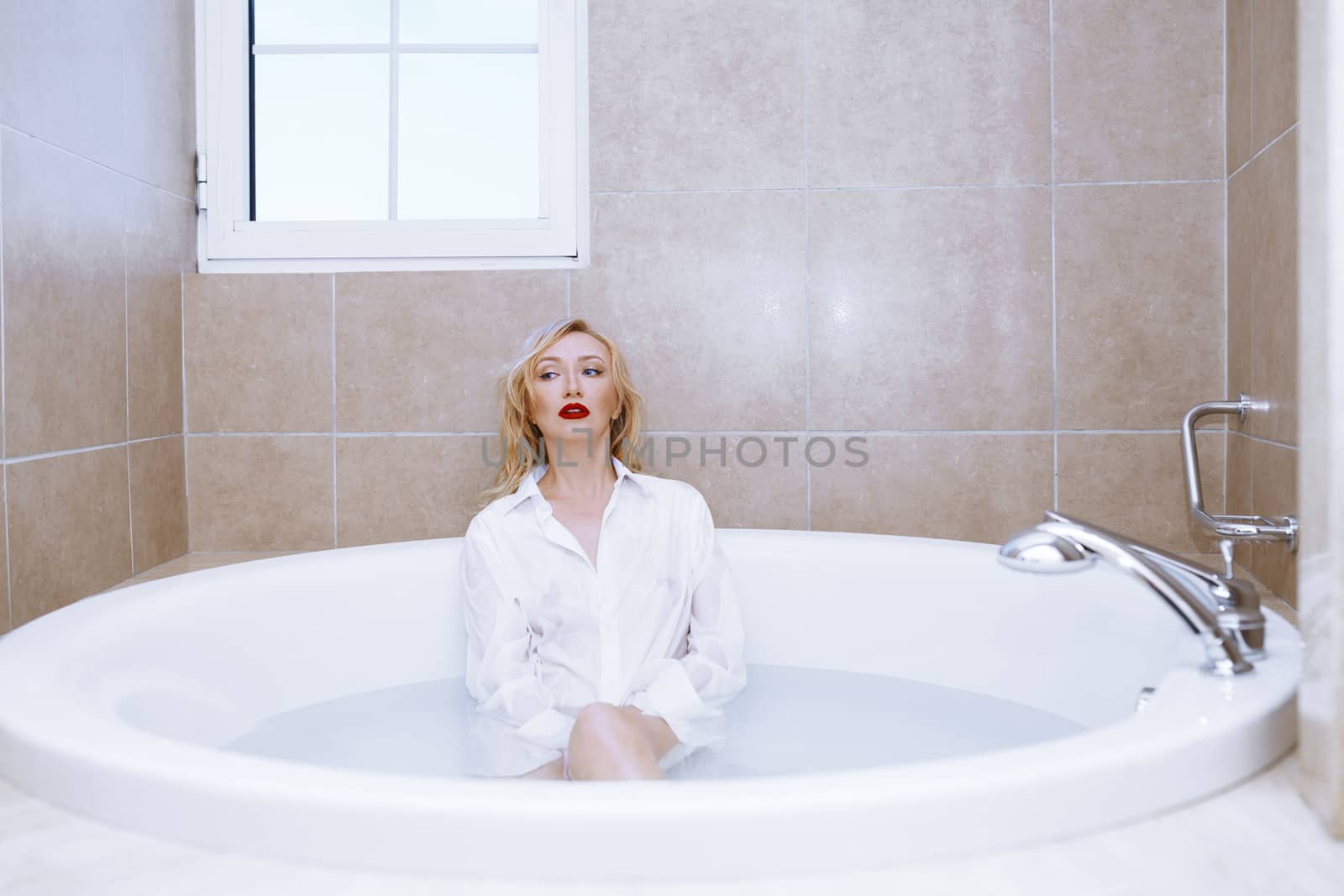 Woman wearing white shirt relaxing in the bath by Novic