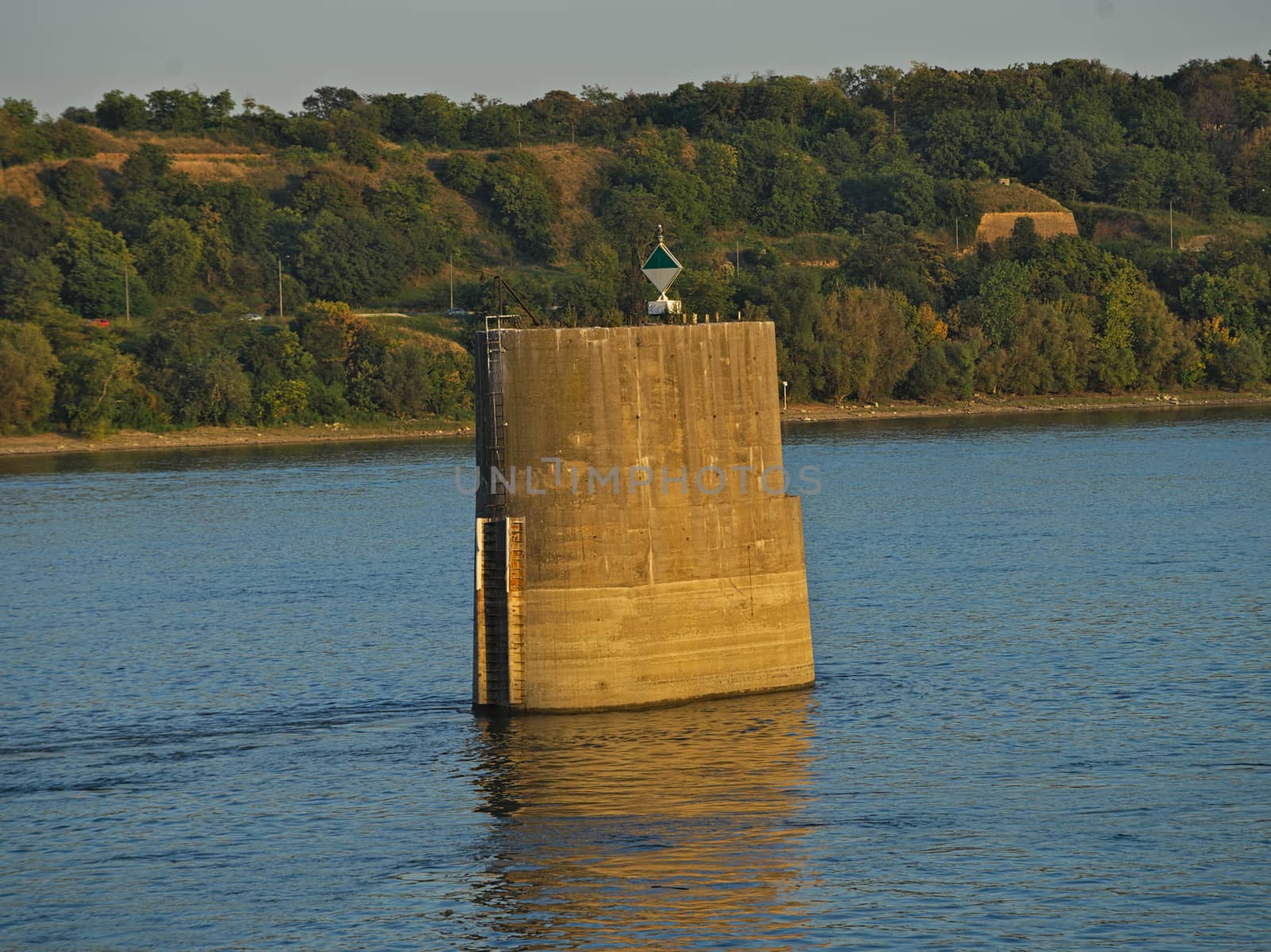 Abandoned old concrete bridge pillar in river with other side behind