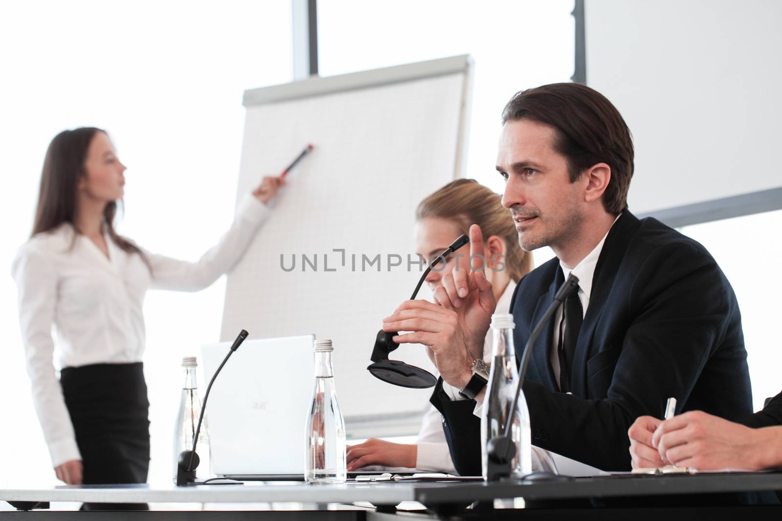 Group of speakers at business meeting at the table with microphones