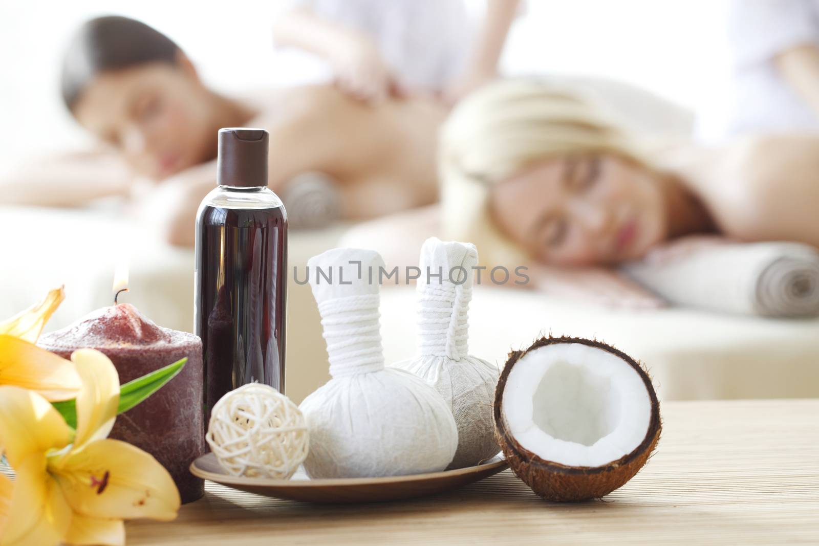 Spa massage tools and women getting massage on background