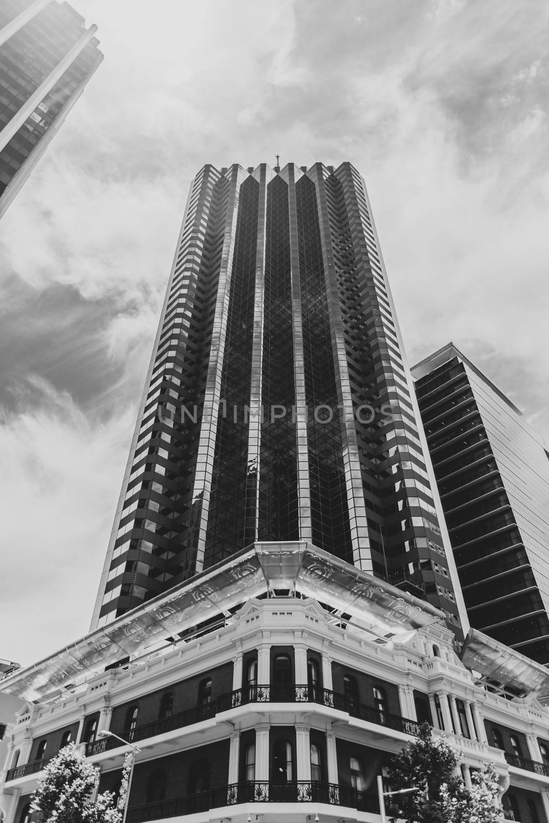 Black and White of old Victorian brick building in front of modern highrise skyscraper in Perth by MXW_Stock
