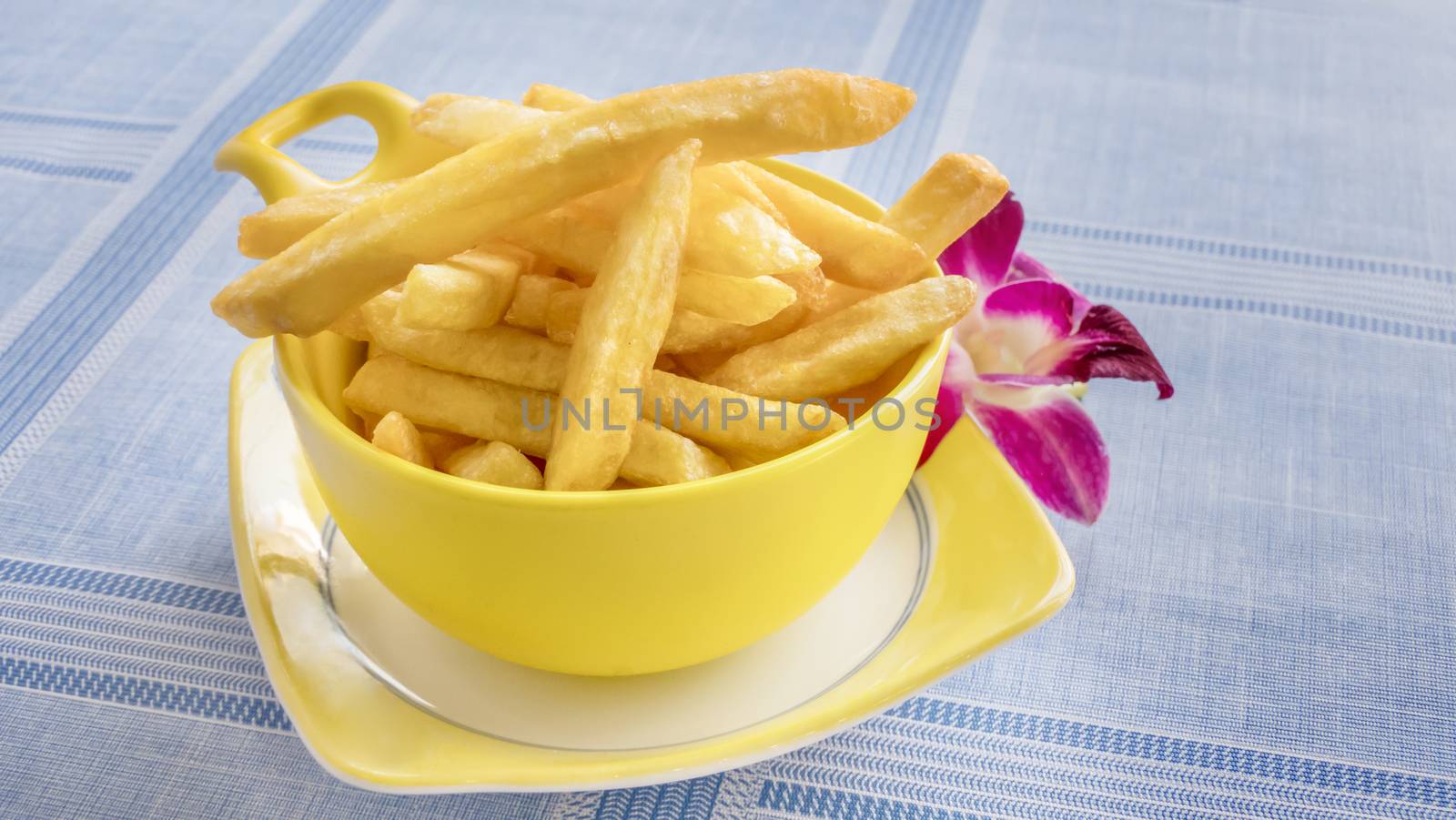 Cups of French fries on table with fresh purple orchid