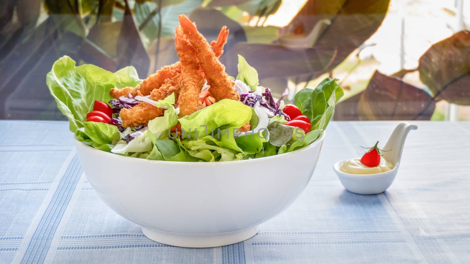 fresh organic salad with deep fried shrimp in white bowl served with cream sauce