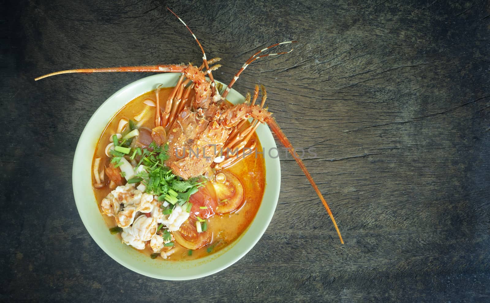 Top view of Tom Yum Goong  , Thai spicy soup in bowl over wooden background