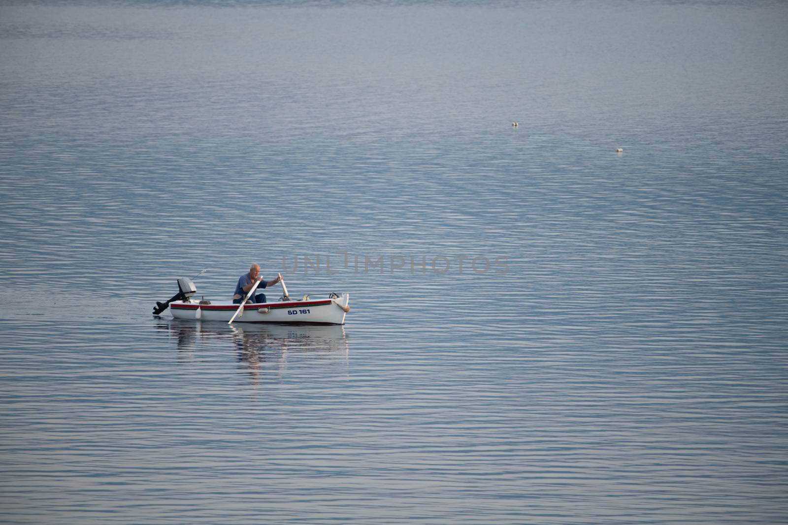 Old traditional fisherman in Croatia on a small wooden boat back into the harbor early morning by asafaric