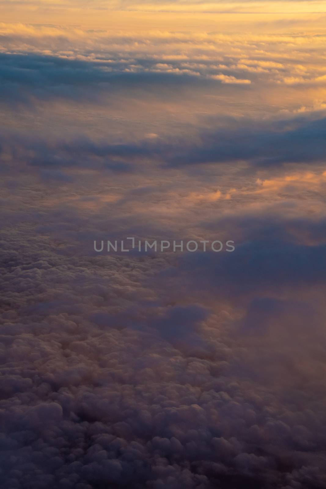 Cloud cover illuminated by sunset half orange and half in earth shadow by MXW_Stock