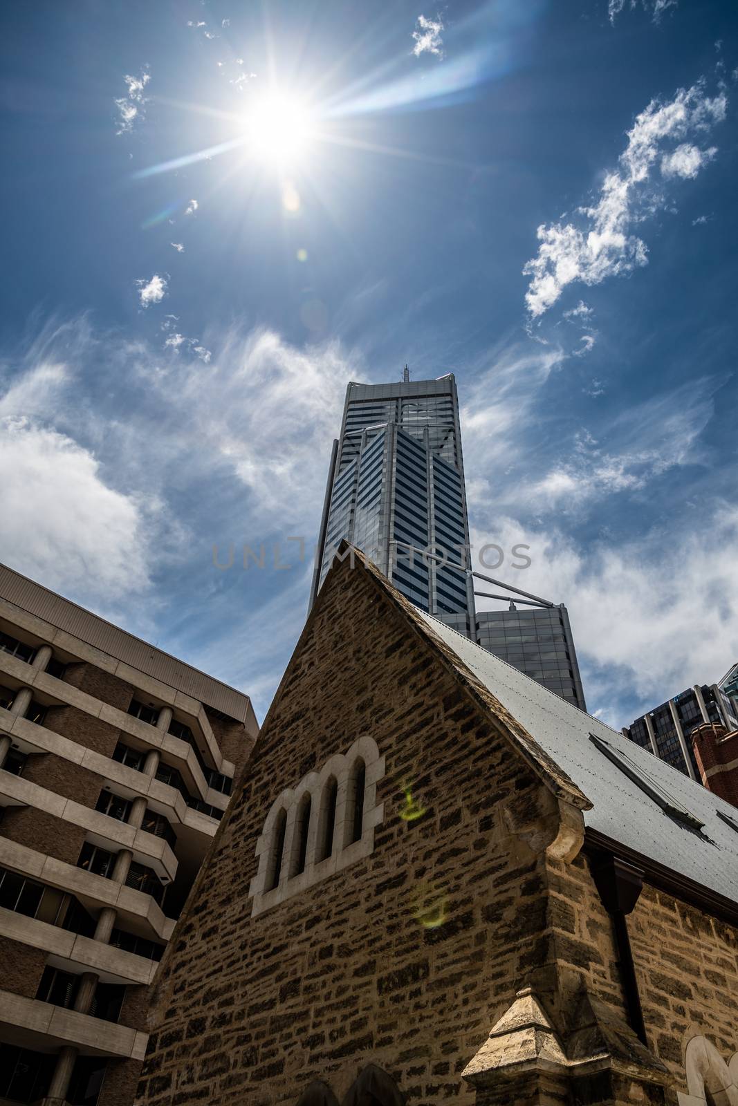 Old nature stone church in front of highrise skyscraper of mining company in Perth by MXW_Stock