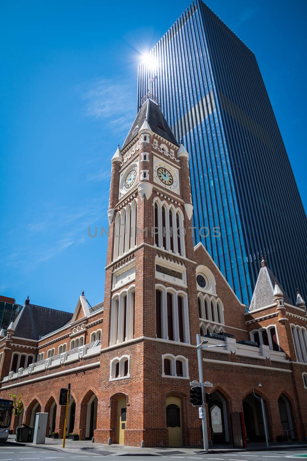 Perth Town Hall in Western Australia old brick building in front of modern skyscraper by MXW_Stock