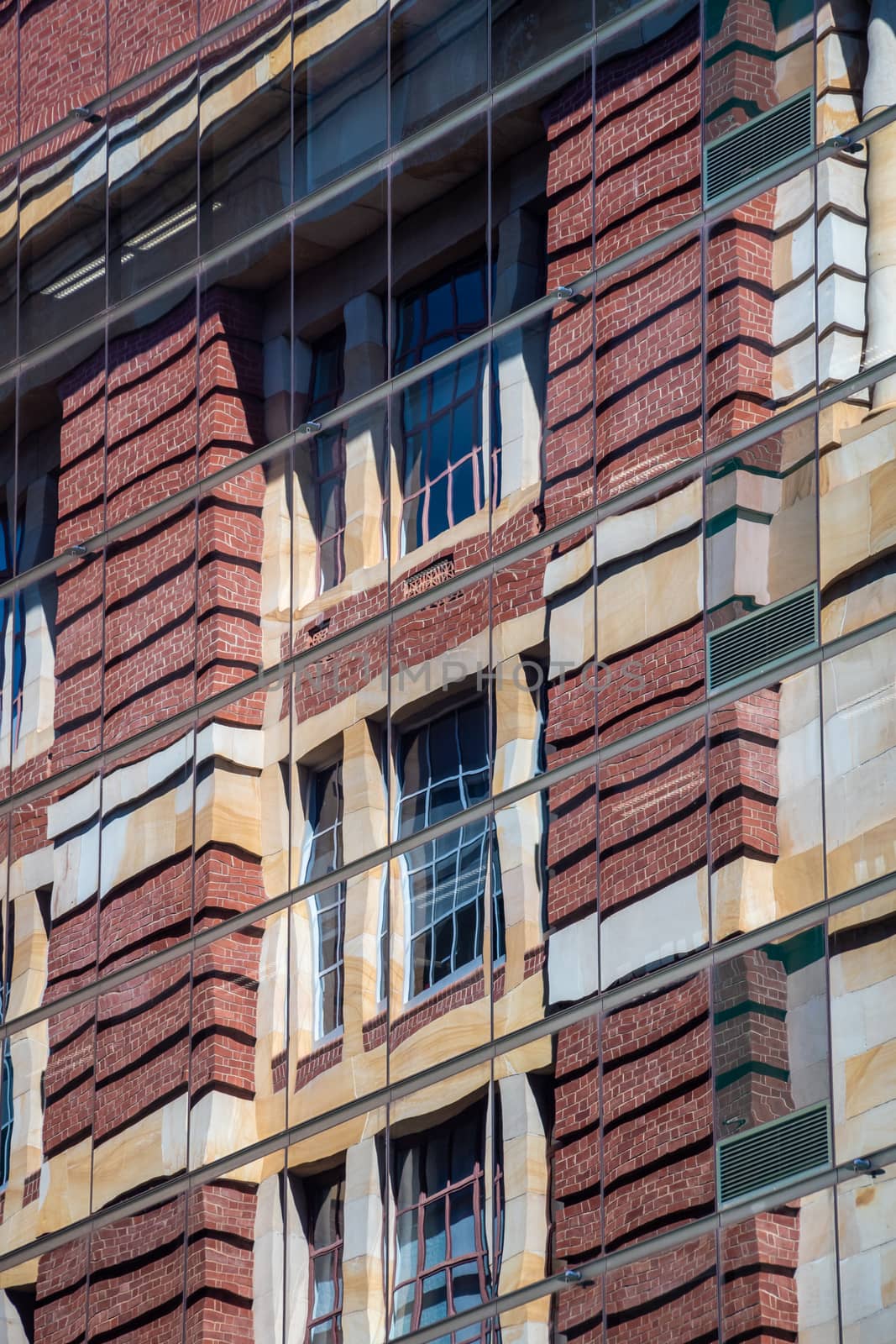Reflection of brick building in modern skyscraper facade with reflective windows by MXW_Stock