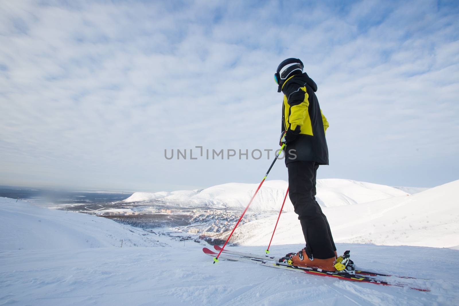 Kirovsk, Russia - Skier on piste in high mountains on ski slope. Rear view. Winter snowboard and skiing concept. Khibiny Mountains, Kola Peninsula panoramic view in town