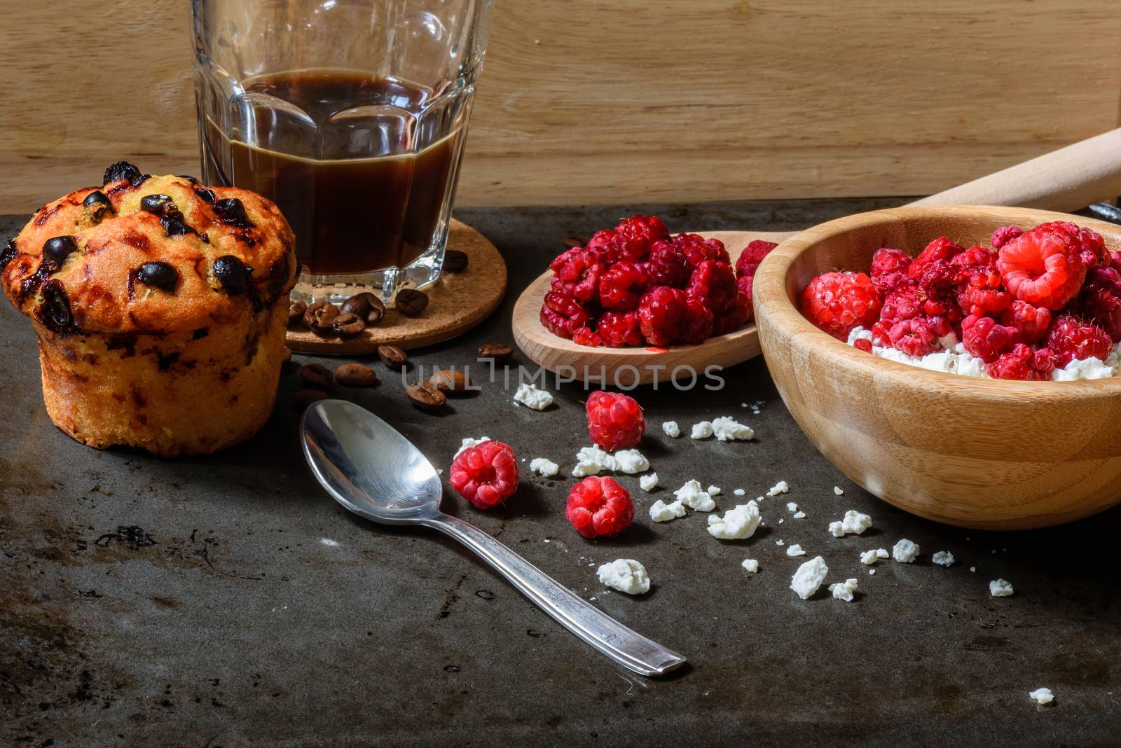 Cottage cheese with raspberries, coffee in a cup and blueberry muffin for breakfast with scattered berries, grains of curd and coffee beans