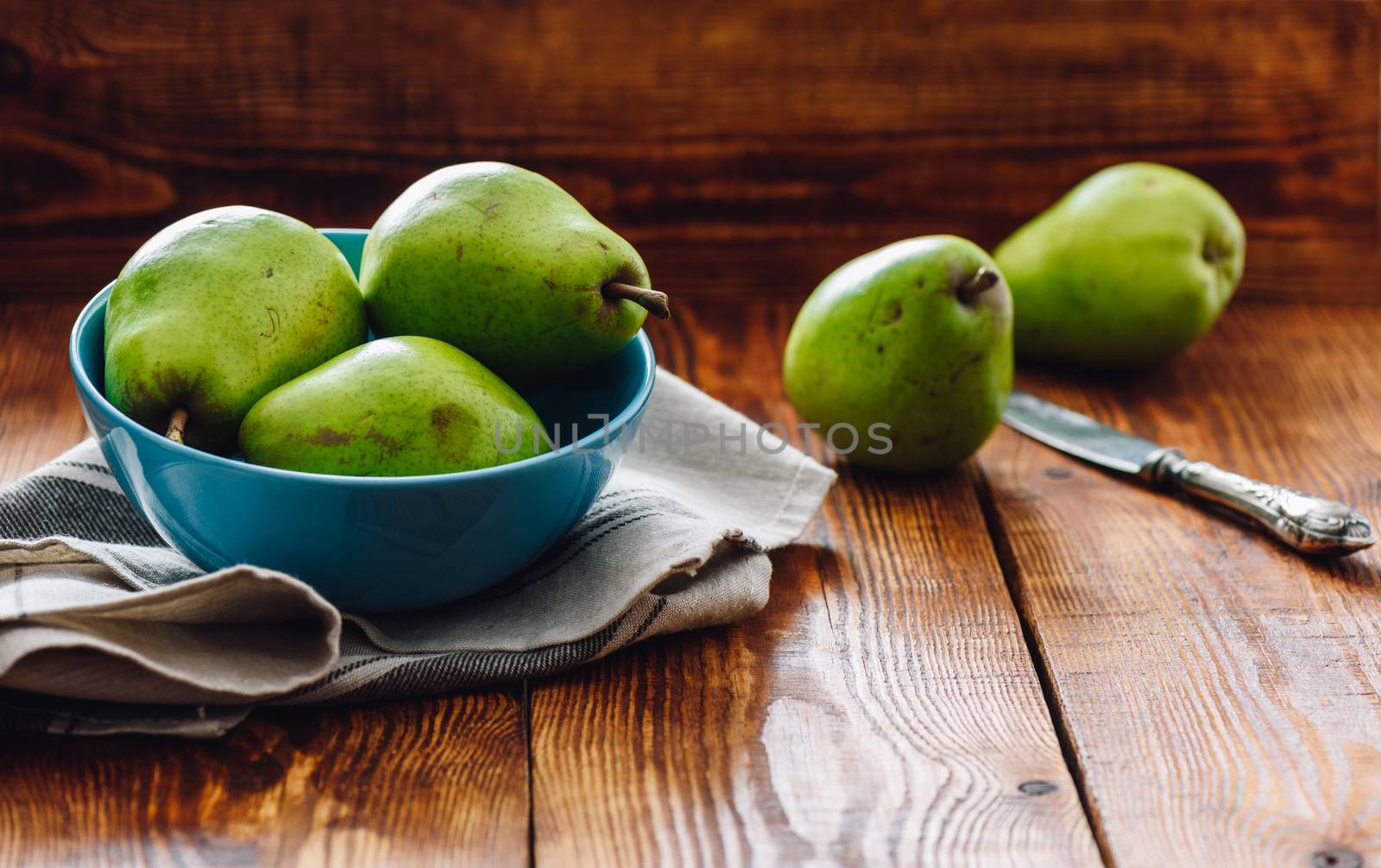 Green Pears in Blue Bowl and Some Pears on Background with Knife.