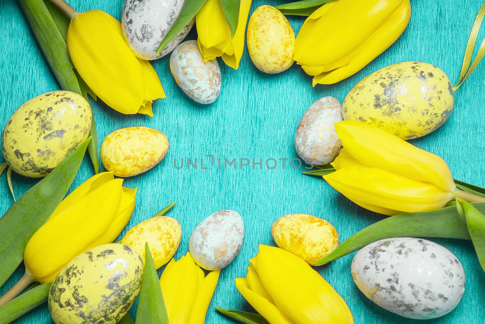Happy Easter. Yellow fresh tulips lie on a blue background with Easter eggs.Happy Easter.