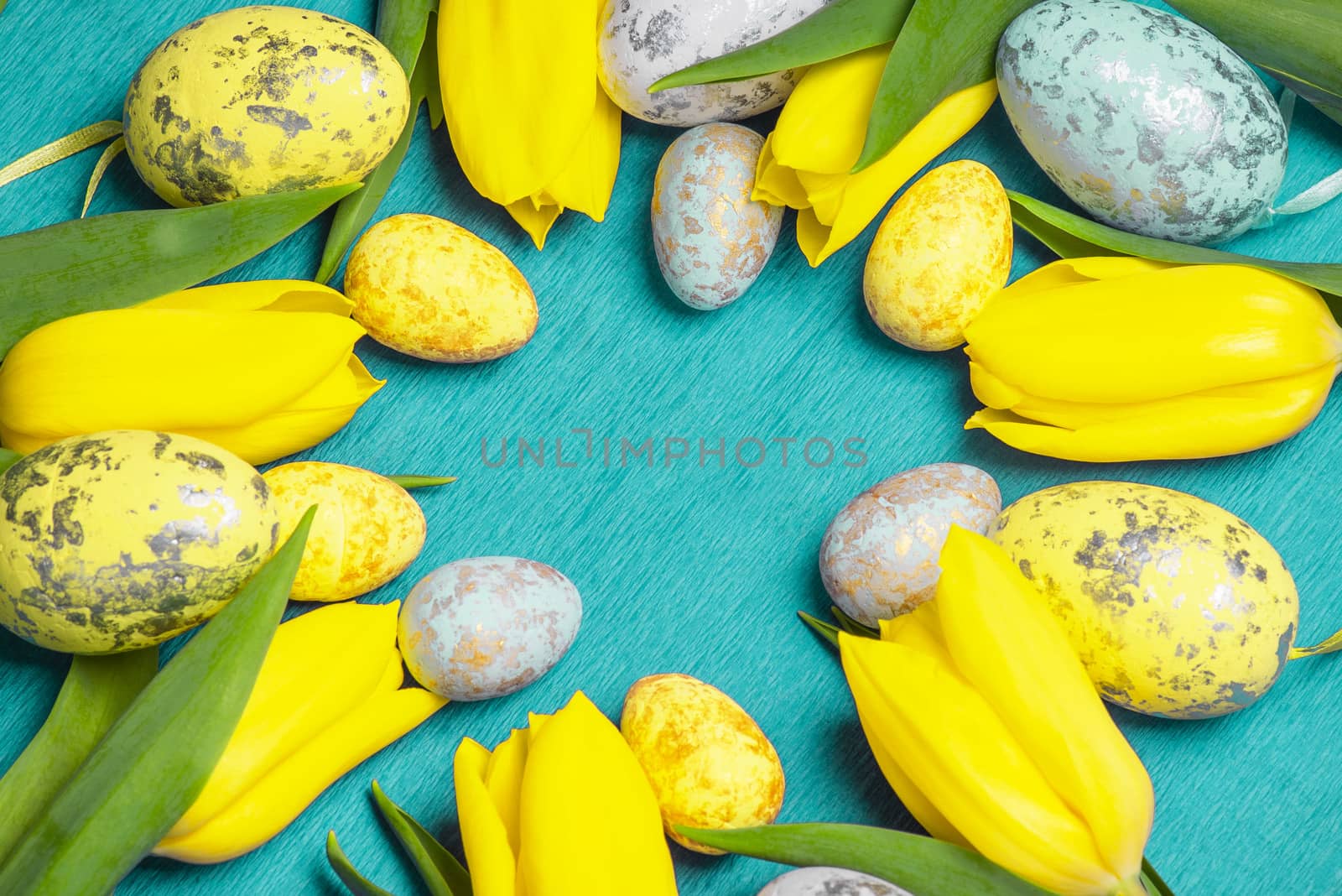 Happy Easter. Yellow fresh tulips lie on a blue background with Easter eggs.Happy Easter.