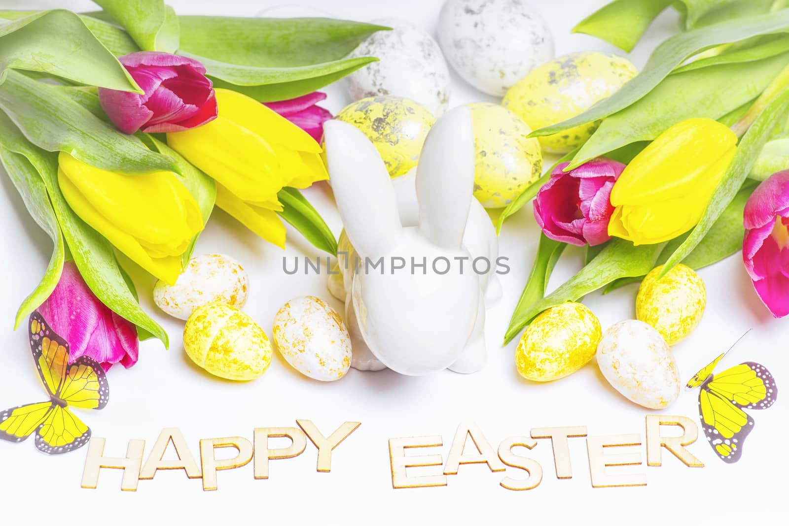 Easter white bunny on a white background with Easter eggs and fresh tulips.Easter greeting card with easter bunny. Easter eggs.Happy Easter.