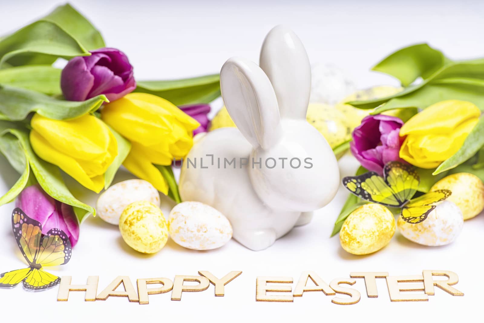 Easter white bunny on a white background with Easter eggs and fresh tulips.Easter greeting card with easter bunny. Easter eggs.Happy Easter.