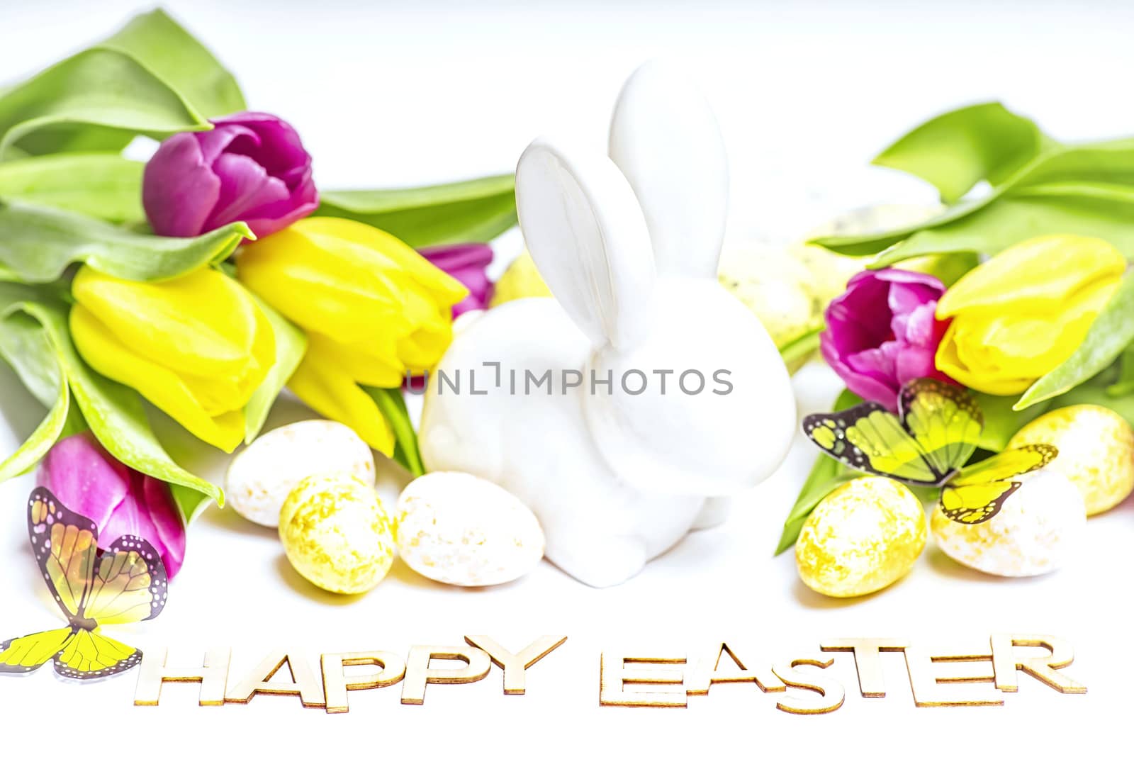 Easter white bunny on a white background with Easter eggs and fresh tulips.Easter greeting card with easter bunny. Easter eggs.Happy Easter.
